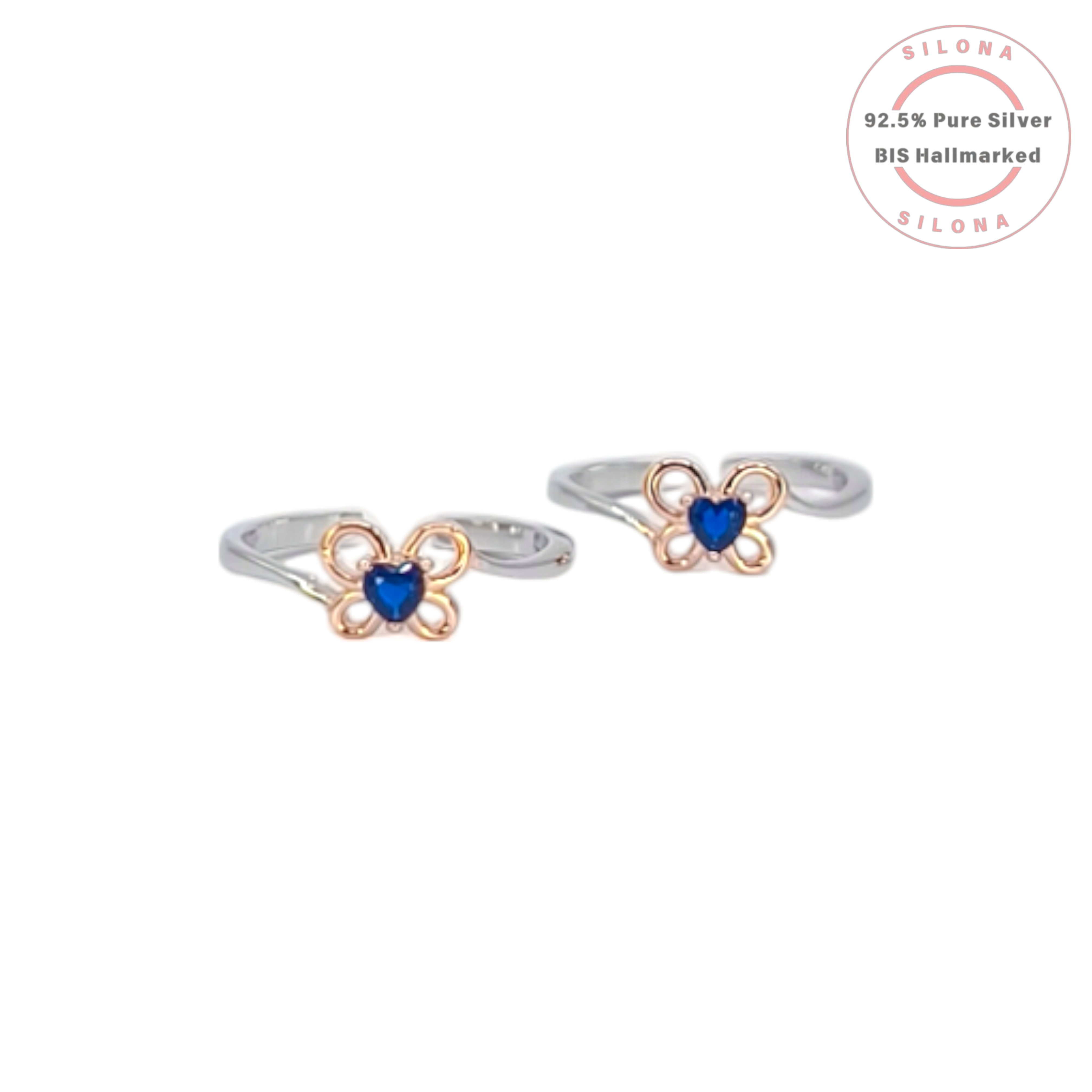 A pair of Silona dual-tone silver toe rings with a rose gold floral motif holding a central heart-shaped sapphire-blue stone on a white background.