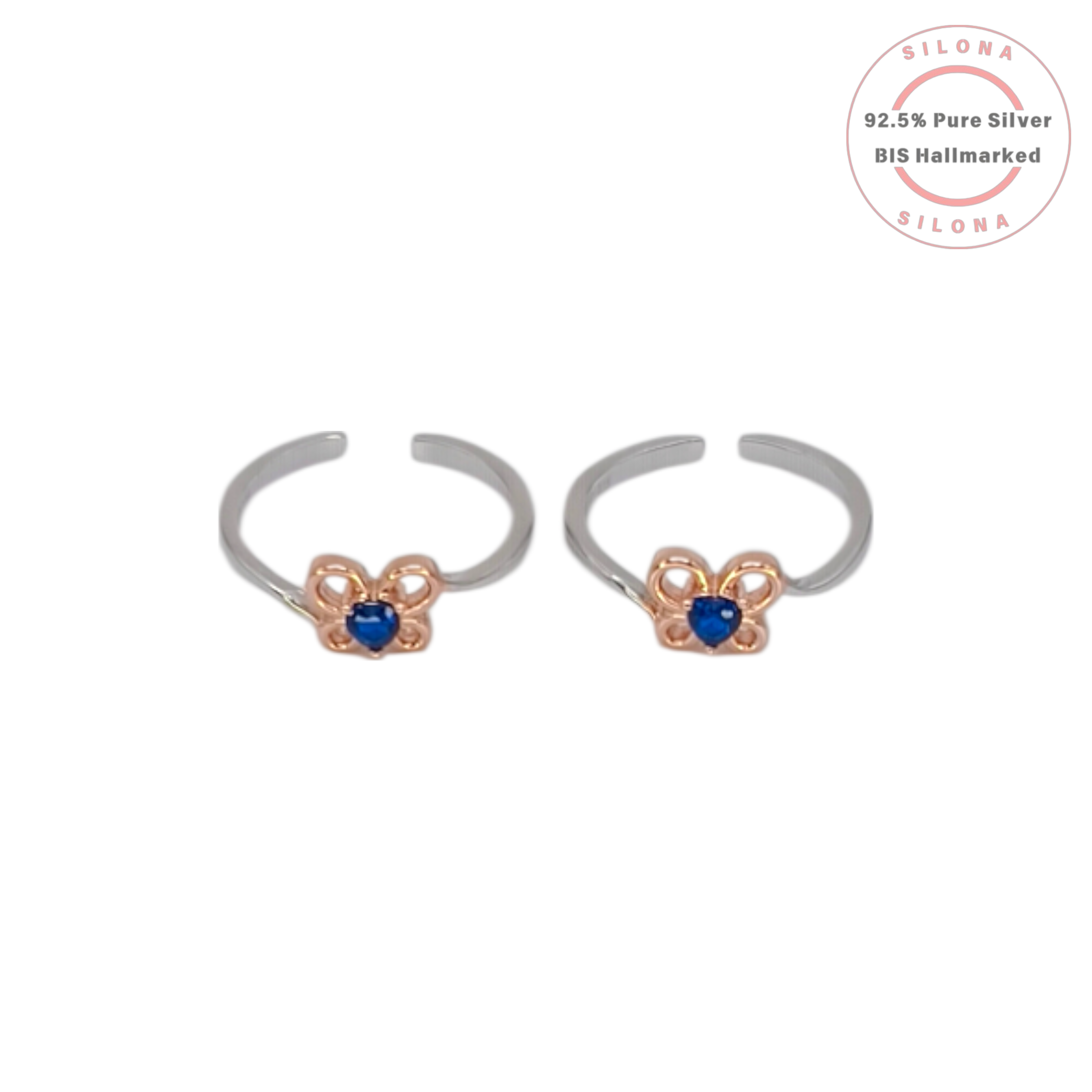 A pair of Silona dual-tone silver toe rings with a rose gold floral motif holding a central heart-shaped sapphire-blue stone on a white background.