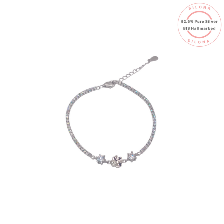 Silona's Dainty Clover Tennis Bracelet in 92.5 silver, featuring a lavender-hued four-leaf clover charm flanked by two solitaires on a sparkling cubic zirconia band, on a white background.