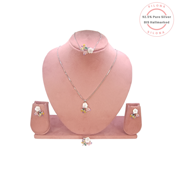 A floral jewellery set featuring a ring and two matching earrings with multi-colored stones, including a carved white flower and a pink enamel flower, on a white background with a Silona logo.