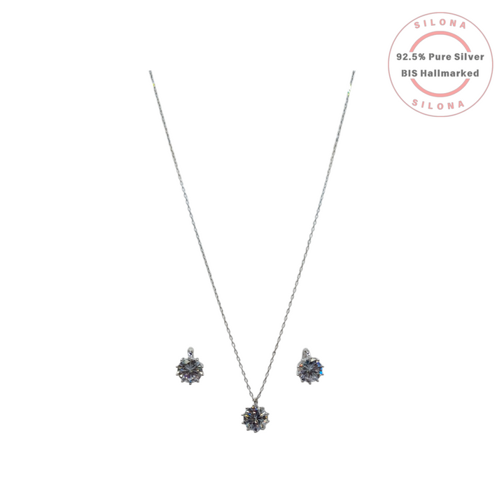 Silona Brilliant Solitaire Necklace Set featuring a silver chain with a round crystal pendant and matching stud earrings, on a white background.