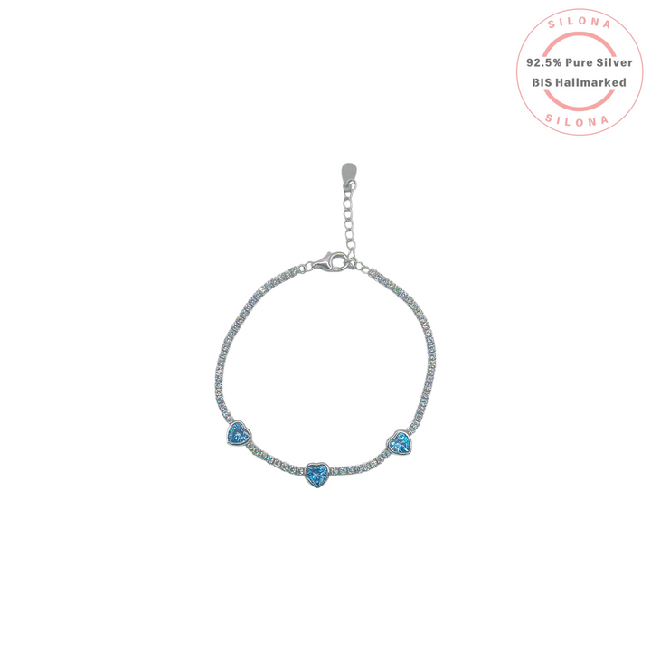 Silona Icy Blue Heart Tennis Bracelet in 92.5 sterling silver, featuring a line of clear cubic zirconia and three light blue heart-shaped stones on a white background.