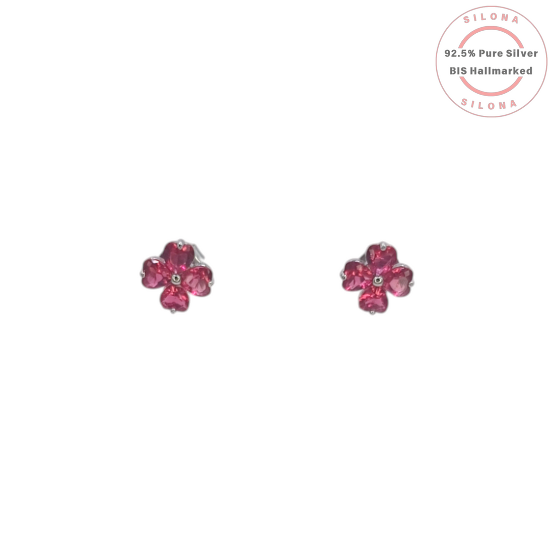 A pair of Silona silver stud earrings shaped like four-leaf clovers with vibrant pink heart-shaped stones on a white background.