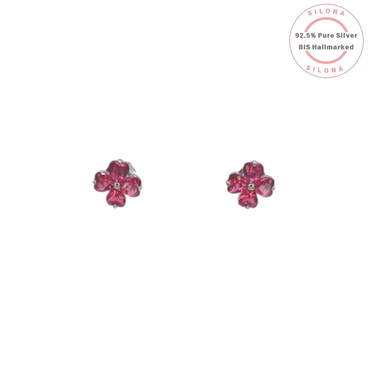 A pair of Silona silver stud earrings shaped like four-leaf clovers with vibrant pink heart-shaped stones on a white background.