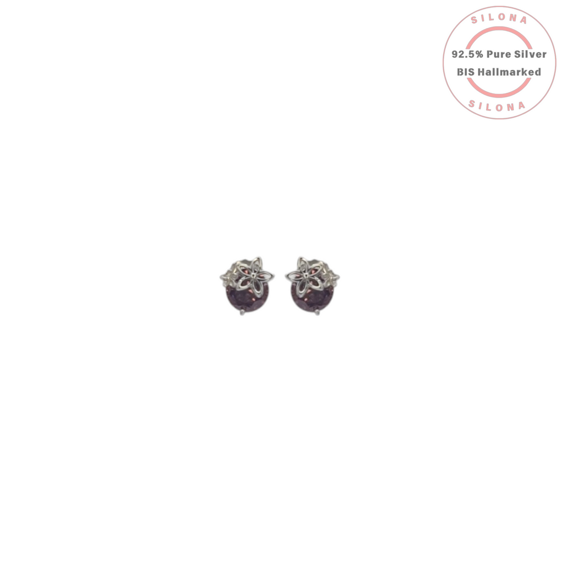 A pair of silver stud earrings featuring a round, sparkling plum-colored stone, each adorned with a silver floral motif on top, against a white background.