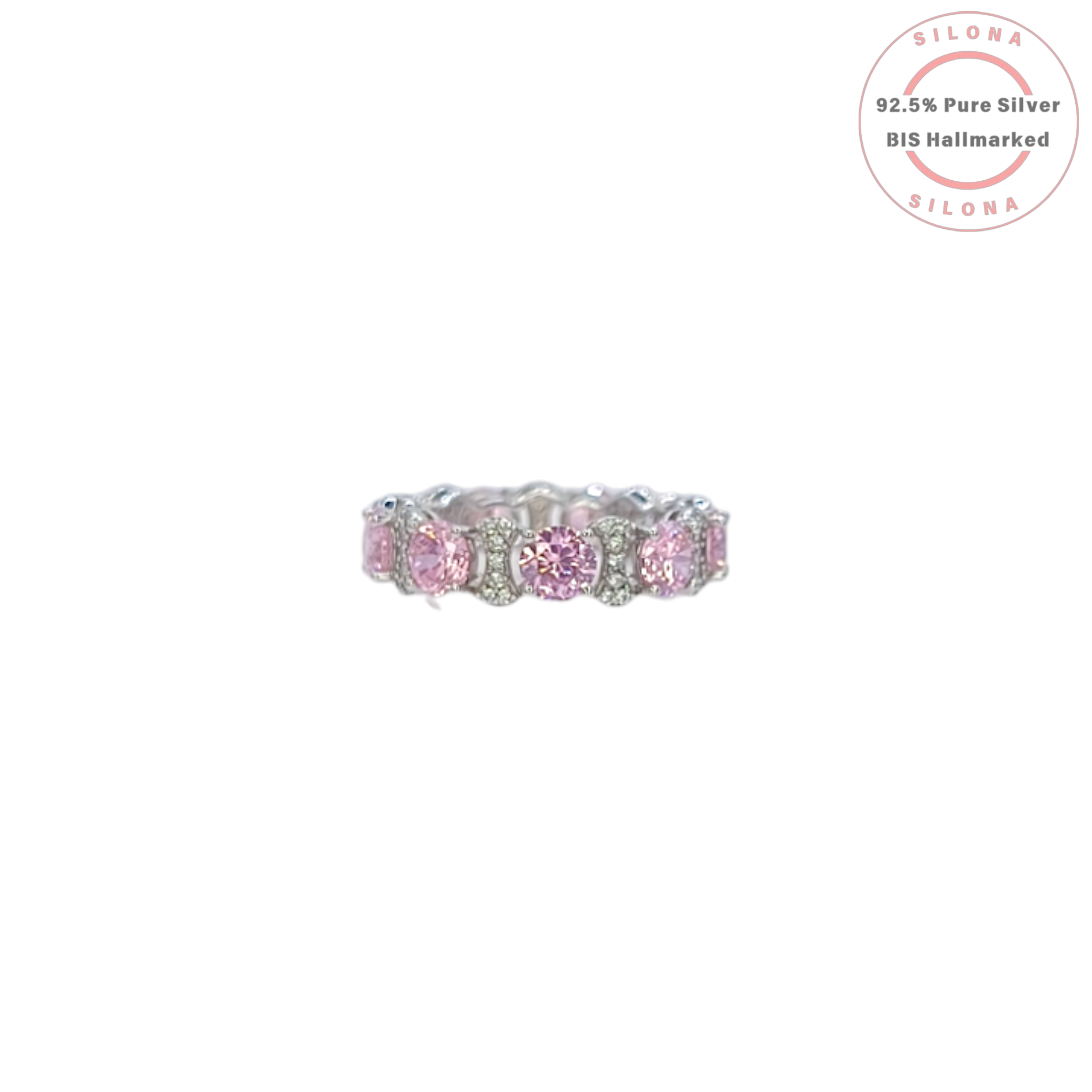 A silver eternity ring featuring large, round, blush pink cubic zirconia stones, interspersed with clusters of small clear pavé stones, on a white background.