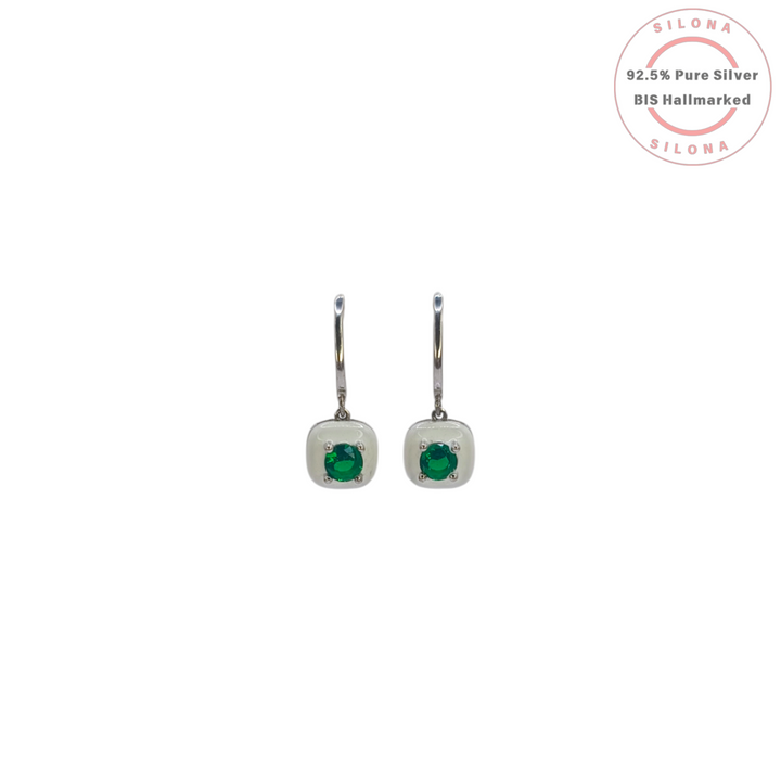 A pair of modern huggie earrings crafted in 92.5 silver, featuring a central emerald-green stone set within a square of white enamel.