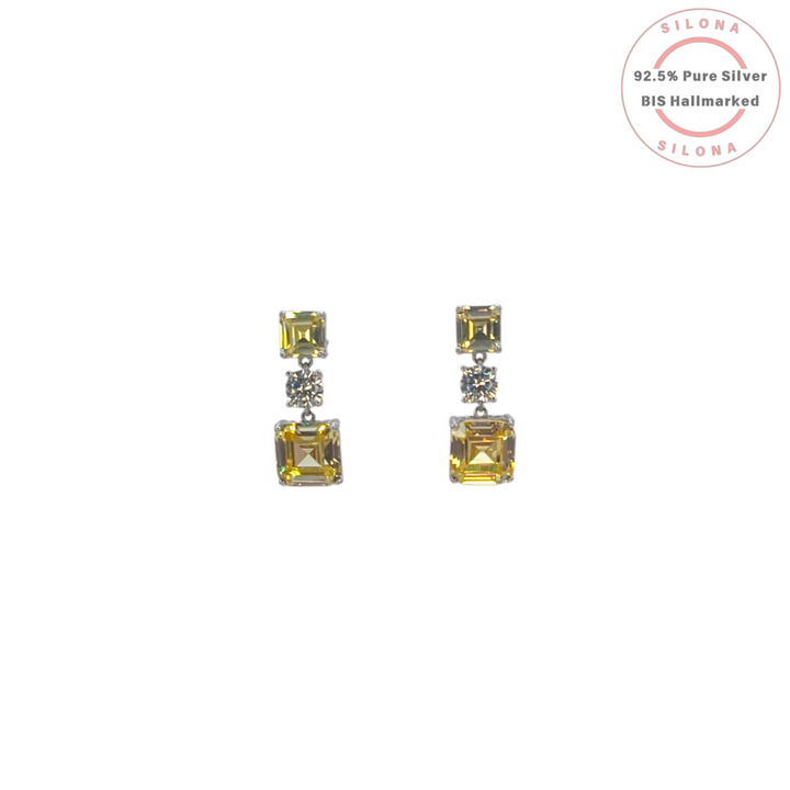 A pair of Silona linear drop earrings in 92.5 silver, featuring square-cut yellow sapphire hue stones and a central round clear cubic zirconia on a white background.