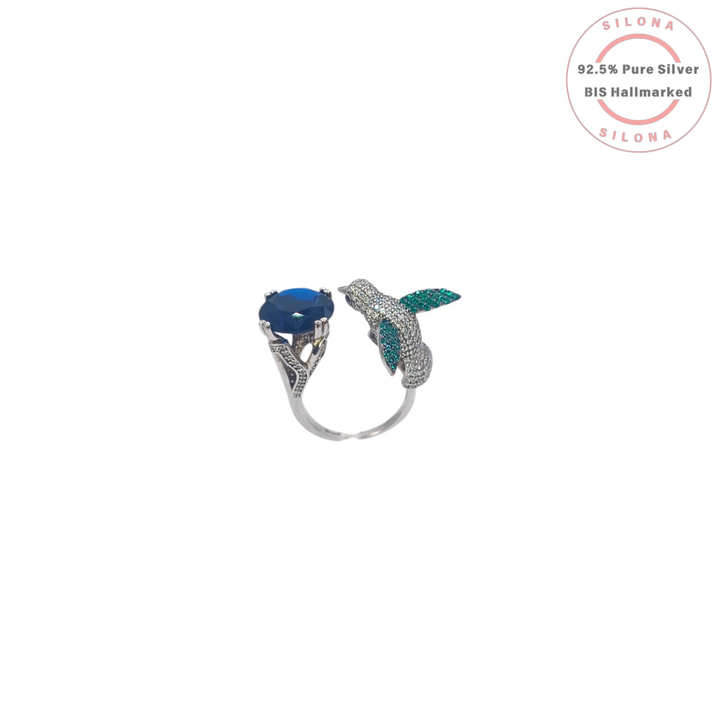 Silona Sculptural Hummingbird Ring in 92.5 silver, featuring a pavé set bird and a large, deep blue faceted stone, on a white background.