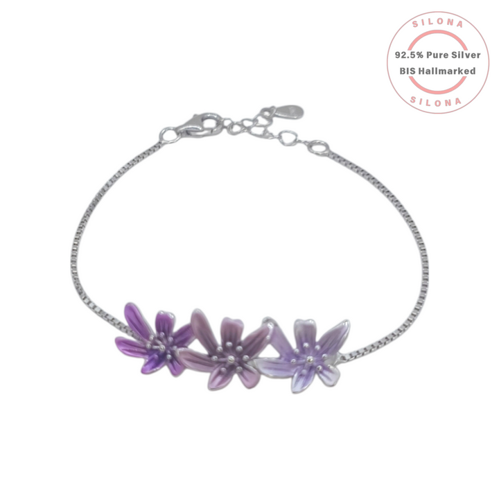 A delicate silver box chain bracelet with three enamel flowers in shades of purple and lavender, crafted from 92.5 pure silver by Silona.