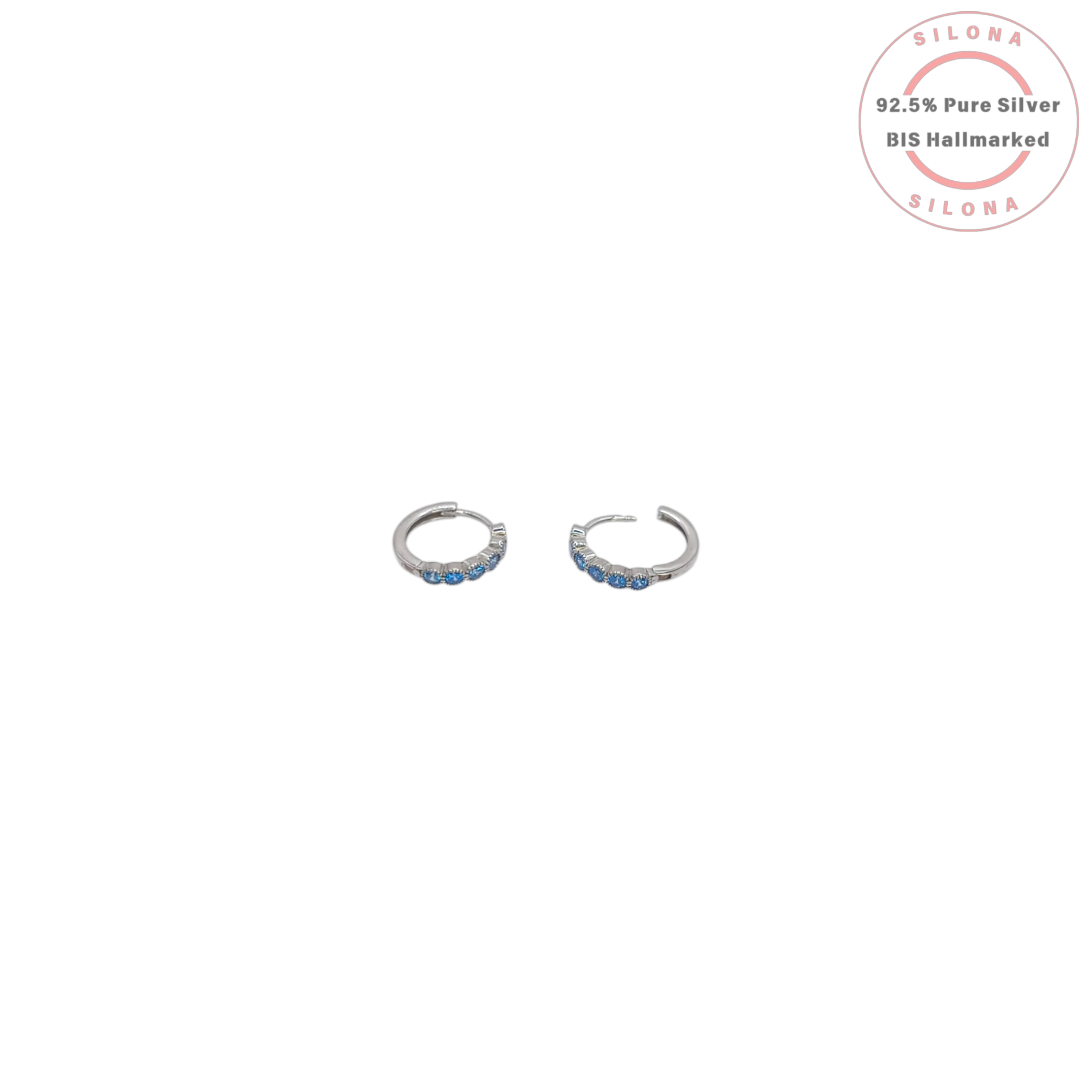 A pair of minimalist silver huggie hoop earrings, each set with a row of small, round, light blue cubic zirconia stones, on a white background with a Silona hallmark.