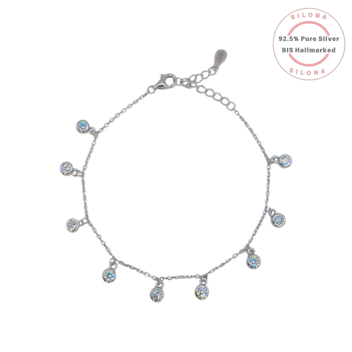 A dainty silver charm bracelet with multiple round bezel-set cubic zirconia stones dangling from a fine chain, on a white background.