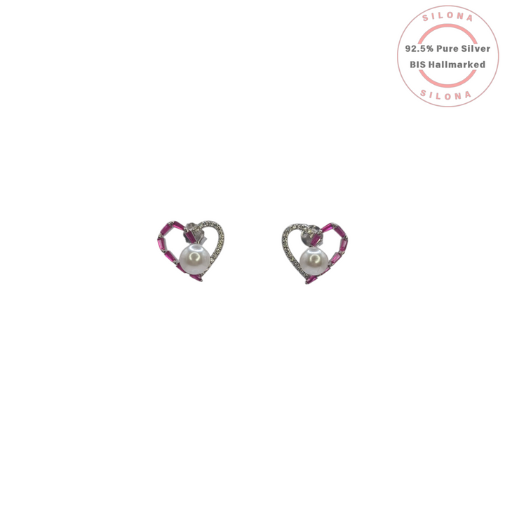 A pair of Silona Amour Heart Stud Earrings in 92.5 silver, featuring a central pearl with one side of ruby-hued baguette stones and the other with pavé cubic zirconia, on a white background.