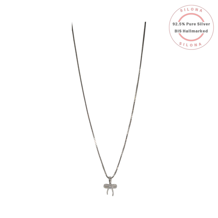 Dainty silver bow necklace paved with cubic zirconia stones, hanging from a sterling silver box chain against a white background.