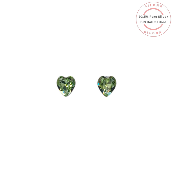 Pair of Silona silver stud earrings with faceted, peridot green, heart-shaped crystals on a white background.