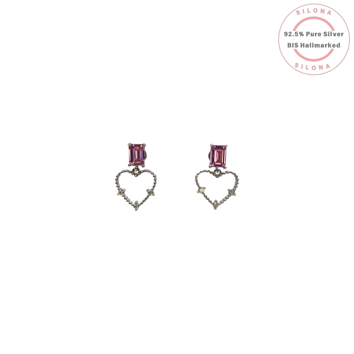 A pair of Silona silver drop earrings featuring a rectangular amethyst-hued stone stud, from which dangles an open-heart silhouette studded with tiny clear gems.