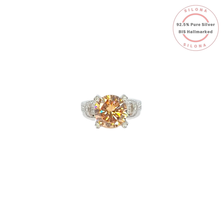 Front view of a statement solitaire ring with a large, round-cut champagne cubic zirconia on a pavé-detailed 92.5 silver band.