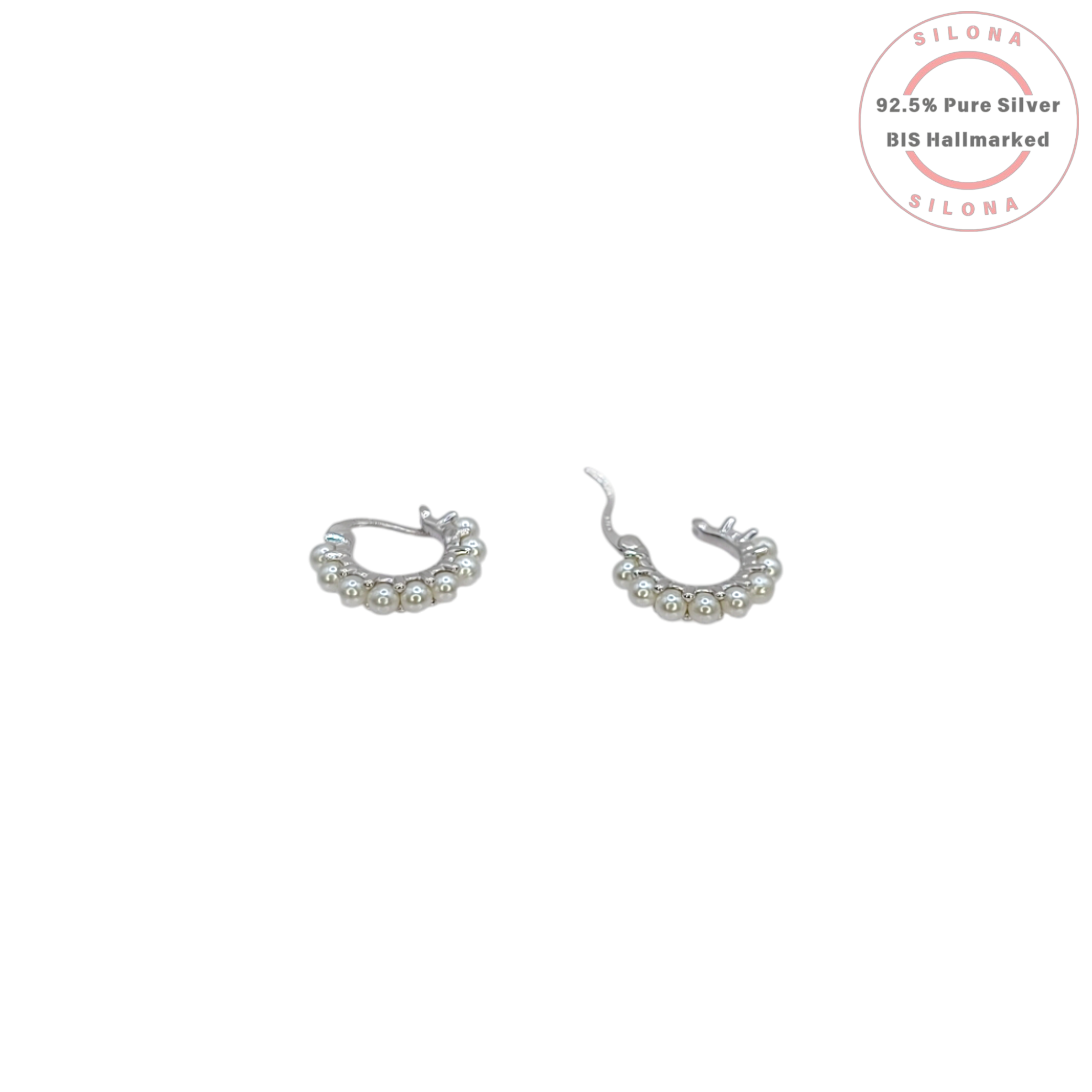 A pair of modern silver huggie hoop earrings, each adorned with a row of small white pearls, on a white background.