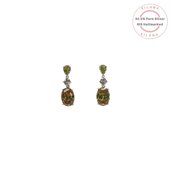 A pair of Silona Luxe Drop Earrings in 92.5 silver, featuring a pear-cut peridot-hued stone and a large oval mystic-hued stone on a white background.
