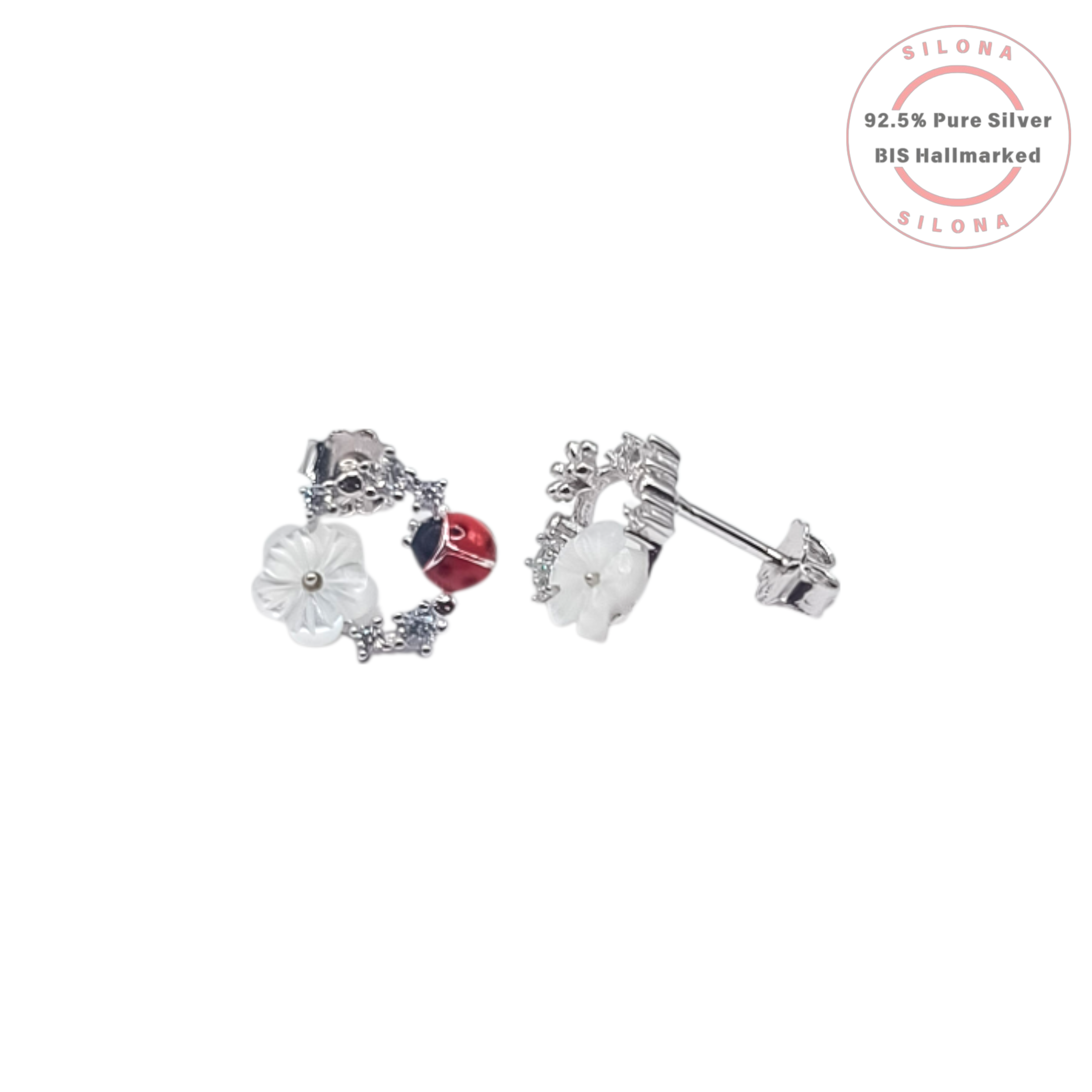 A pair of asymmetrical silver stud earrings, one with a mother-of-pearl flower and the other with a red enamel ladybug, both accented with sparkling cubic zirconia.