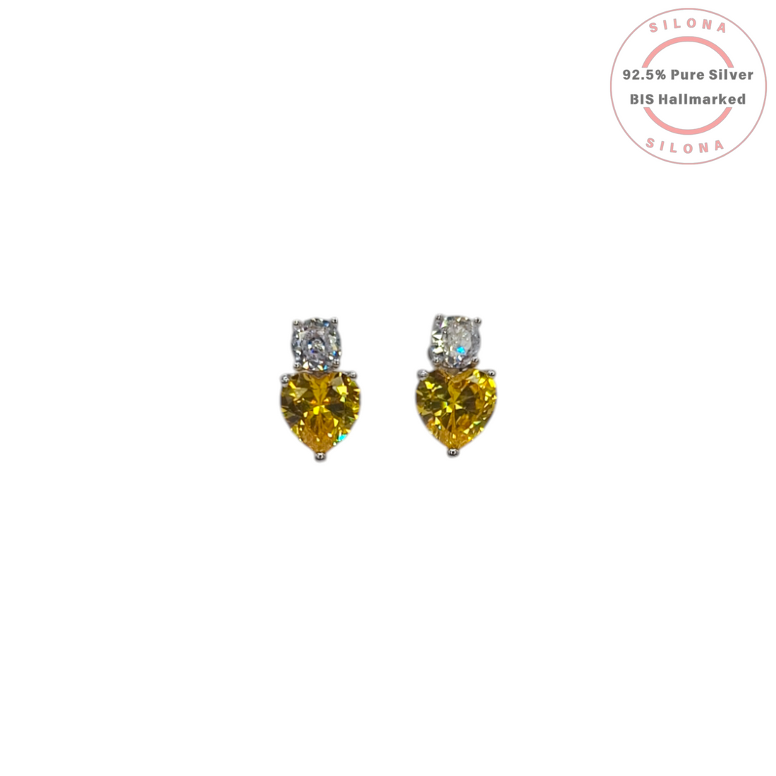 A pair of Silona silver stud earrings, each featuring a heart-shaped canary yellow cubic zirconia stone below a small, round, clear cubic zirconia stone, on a white background.