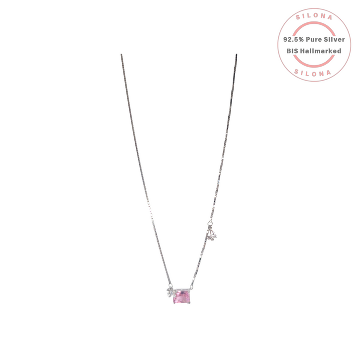Delicate silver box chain necklace featuring a rectangular blush pink solitaire crystal with a small floral accent, on a white background.