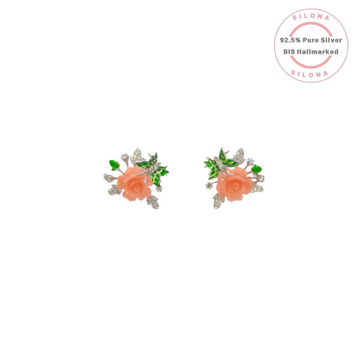 Pair of Silona silver stud earrings featuring a carved coral-colored rose with green enamel leaves and sparkling cubic zirconia accents on a white background.