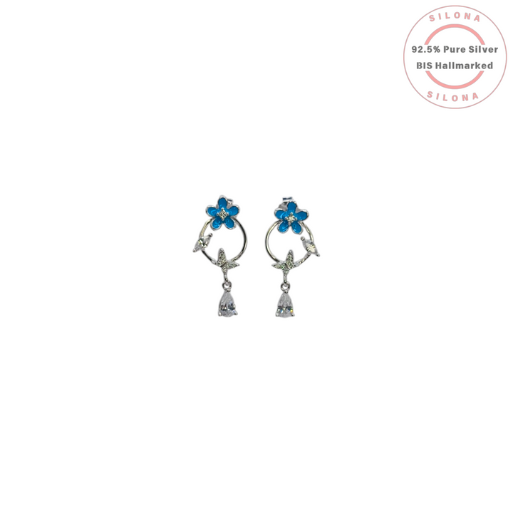 A pair of Silona's Enamel Blue Flower Drop Earrings in 92.5 silver, featuring a blue enamel flower, crystal vine, and a dangling pear-shaped cubic zirconia stone on a white background.