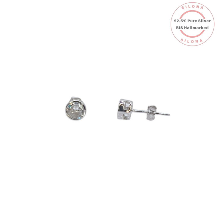 A pair of Classic Solitaire Stud Earrings in 92.5 sterling silver, one shown from the front with a bezel-set cubic zirconia and the other from the side, on a white background with the Silona hallmark seal.