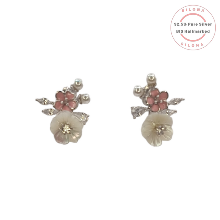 A pair of Silona silver floral stud earrings featuring a carved mother of pearl flower, a pink enamel blossom, and cubic zirconia leaf details on a white background.