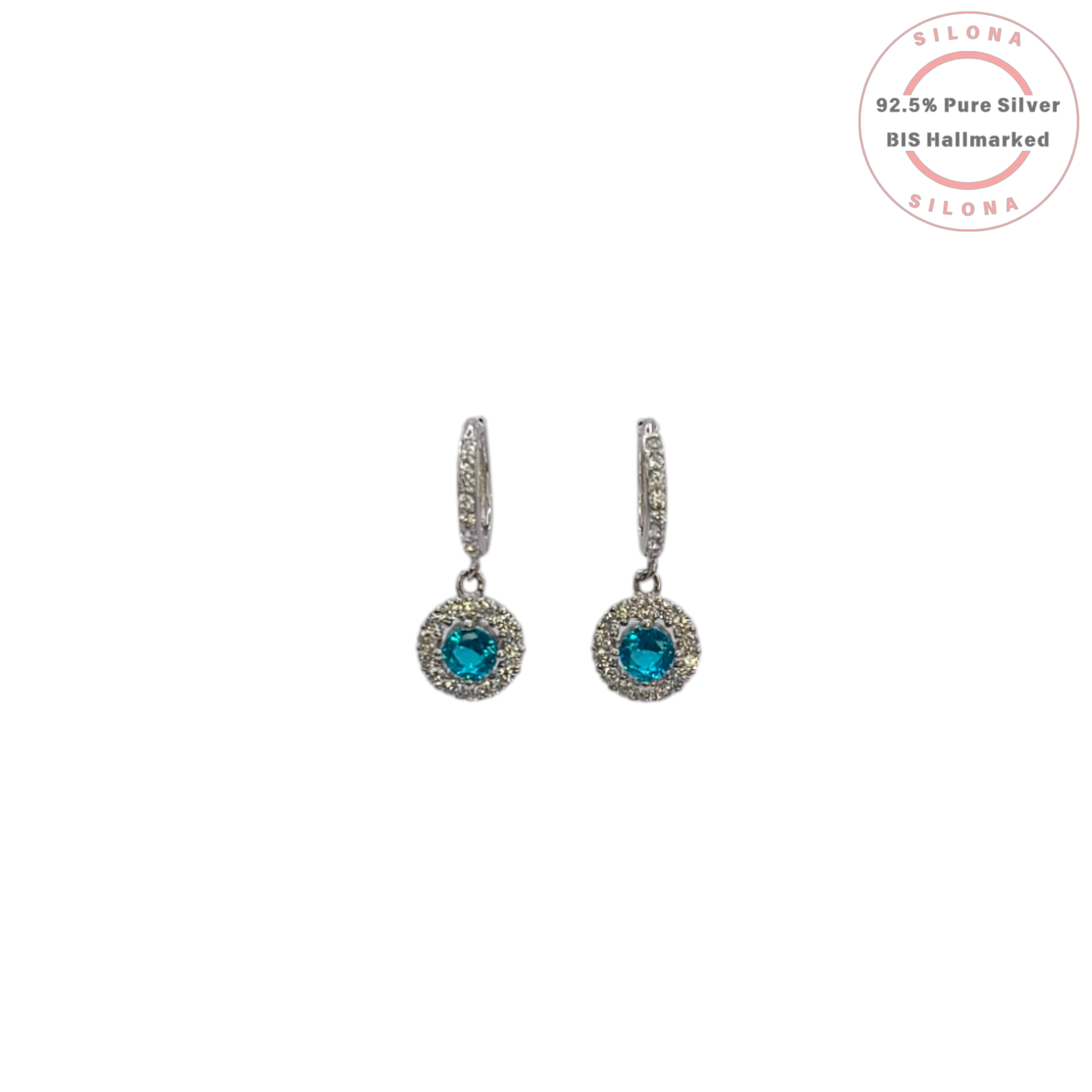 A pair of Silona silver huggie hoop earrings with a dangling round halo charm featuring a central aquamarine blue cubic zirconia stone, on a white background.