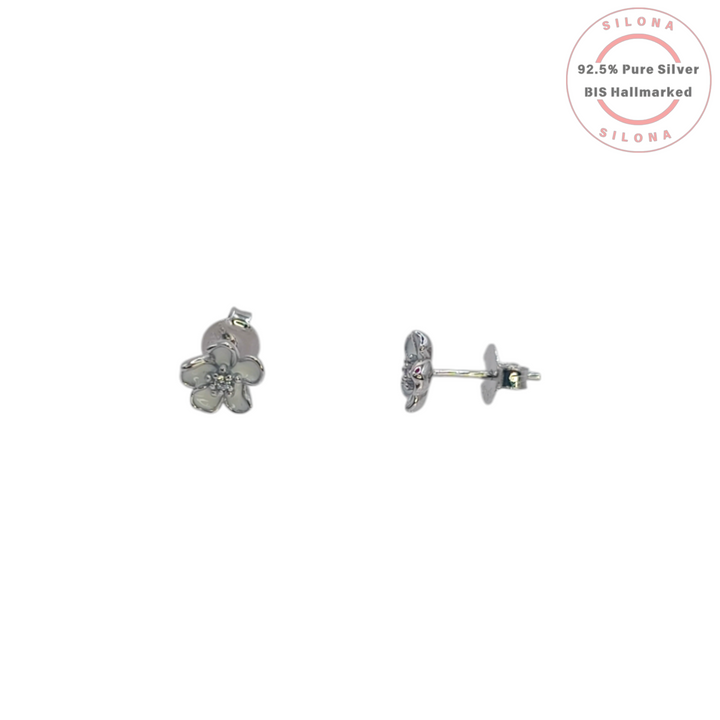 A pair of Ethereal Blossom Stud Earrings in 92.5 silver, featuring a five-petal flower design with creamy enamel and a sparkling center, displayed on a white marble surface.