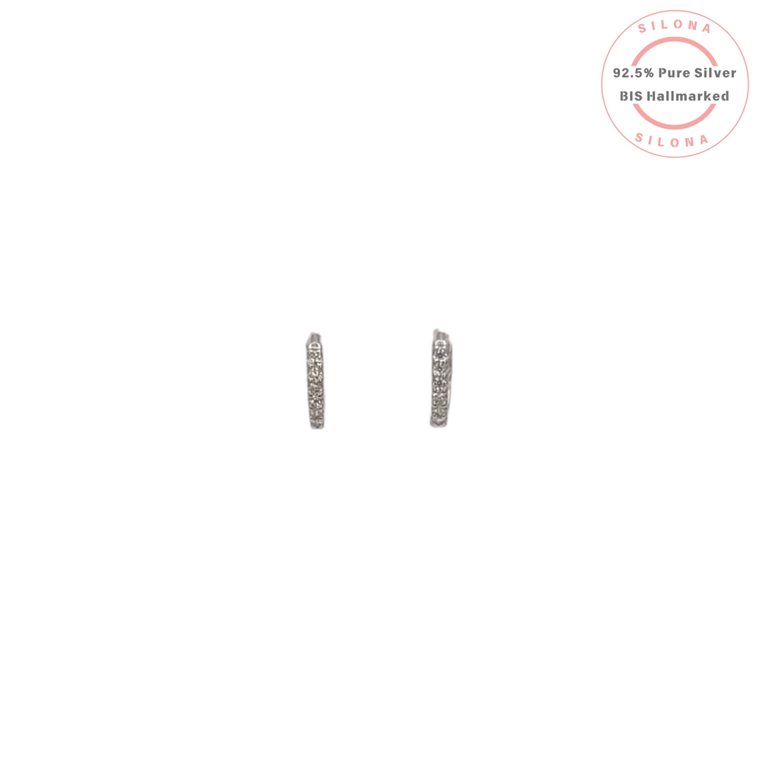 A pair of minimalist pavé cubic zirconia huggie earrings in 92.5 sterling silver on a white background.