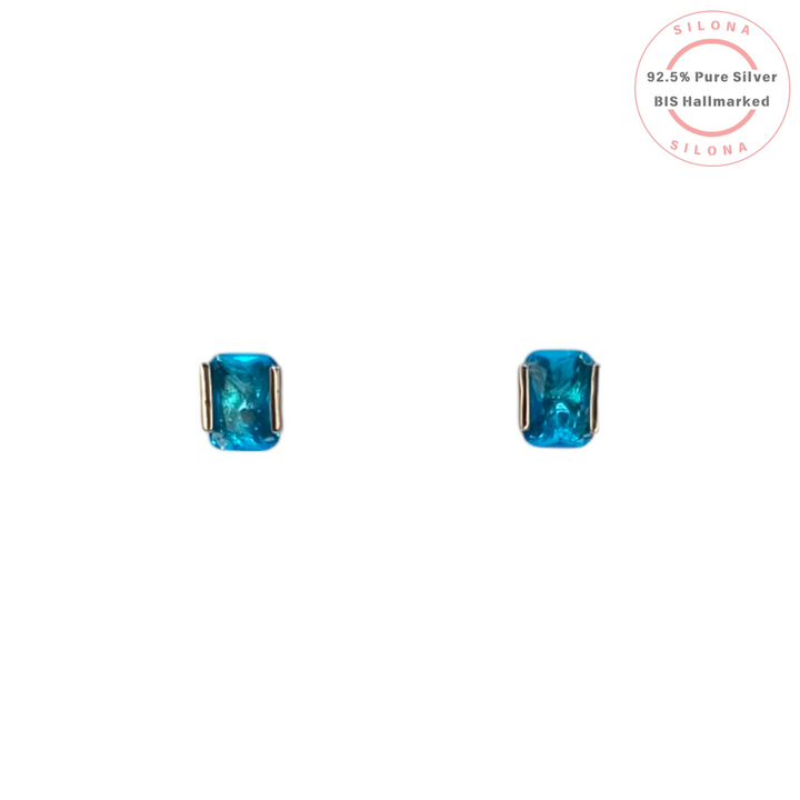 Pair of Solitaire Cushion Cut Stud Earrings with Swiss Blue Hue Stones in 92.5 Silver on a white background.