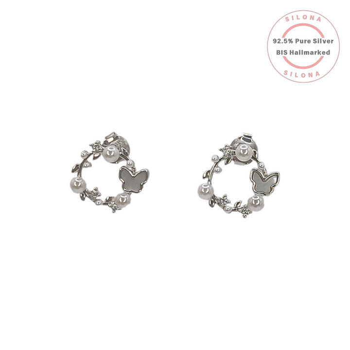 A pair of Silona's Ethereal Butterfly Wreath Earrings in 92.5 silver, featuring a mother-of-pearl butterfly, white pearls, and crystal leaves on a white background.
