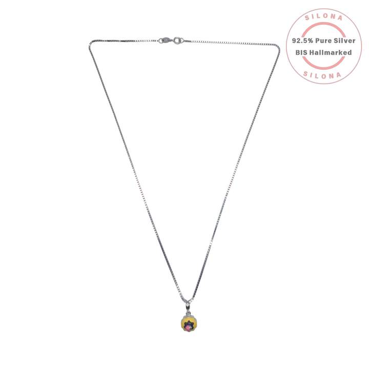 A minimalist silver box chain necklace featuring a small, round yellow enamel charm with a black and pink pop art floral design, on a white background.