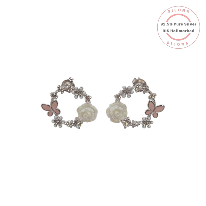 A pair of silver wreath stud earrings featuring a white mother-of-pearl rose, a pink enamel butterfly, and small cubic zirconia stones on a white background.