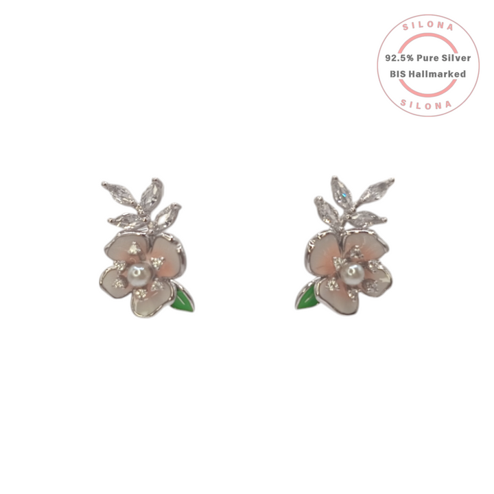 A pair of Silona silver stud earrings shaped like a blush pink enamel flower with a central pearl, marquise CZ leaves, and green enamel details, on a white background.