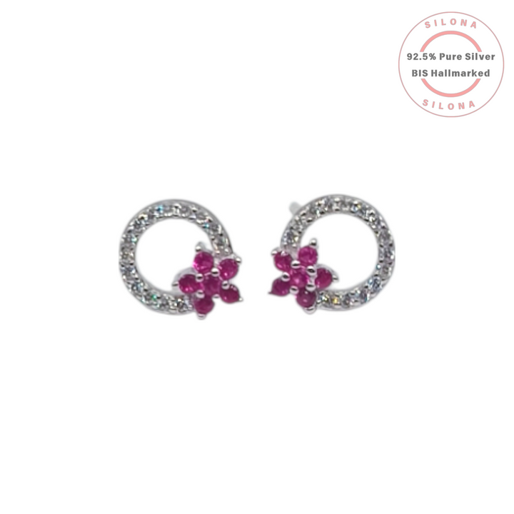 A pair of Silona silver stud earrings featuring a pavé crystal loop with a ruby-hued floral cluster on a white background.