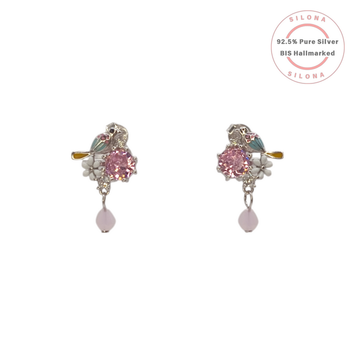 Pair of Silona enamel lovebird stud earrings in 92.5 silver, featuring a large pink cubic zirconia, white enamel flowers, and a dangling pink bead.