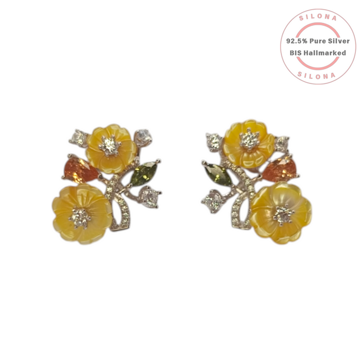 A pair of Silona's Carved Buttercup Floral Stud Earrings, featuring yellow carved flowers, orange and green gems, and clear cubic zirconia, set in 92.5 pure silver on a white background.