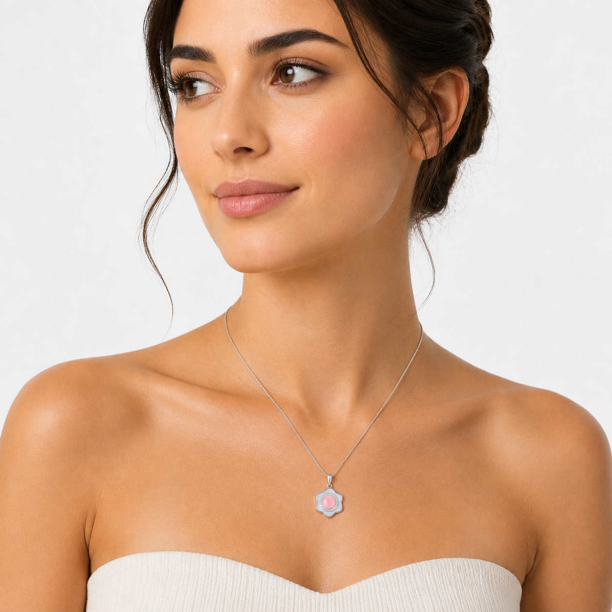 A silver pendant necklace featuring a six-petaled flower frame with a white background, centered around a pink cabochon encircled by clear sparkling stones.