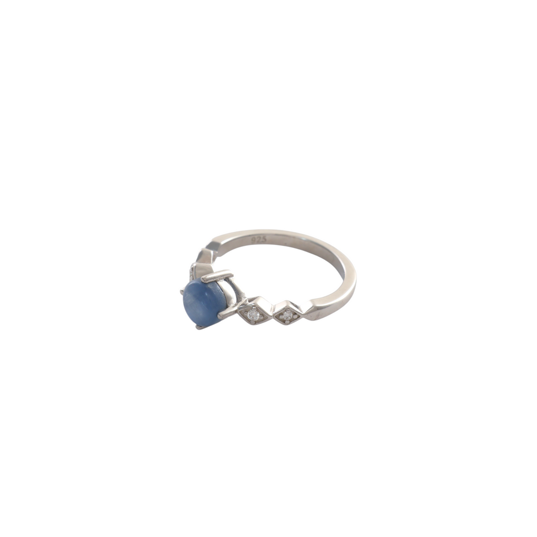 Round blue kyanite cabochon with four prongs set between pave diamond-shaped silver shoulders.