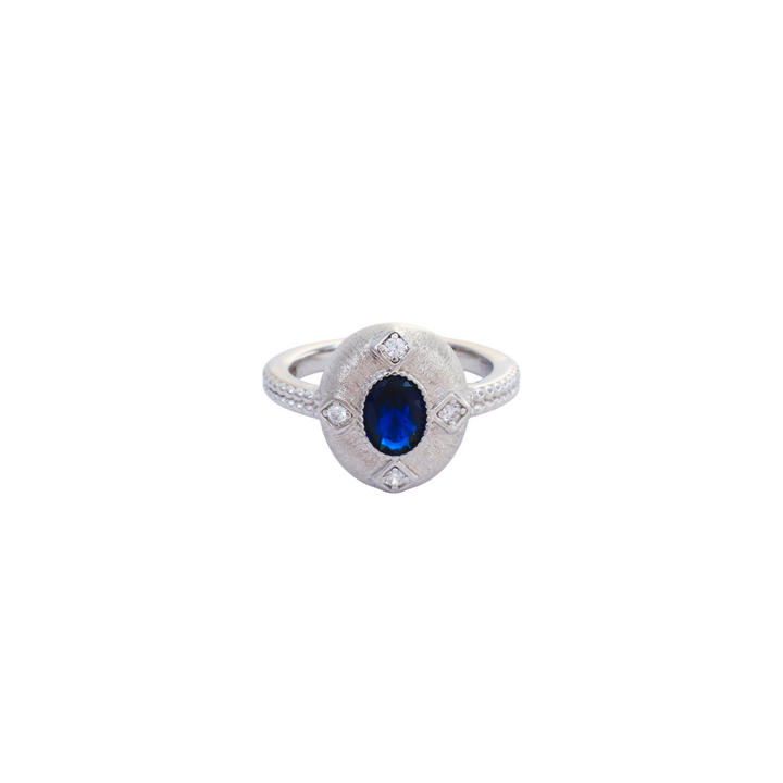Oval sapphire blue gemstone set in a brushed silver medallion setting with pave cz accents.
