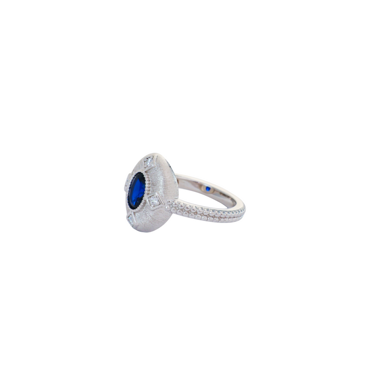 Oval sapphire blue gemstone set in a brushed silver medallion setting with pave cz accents.