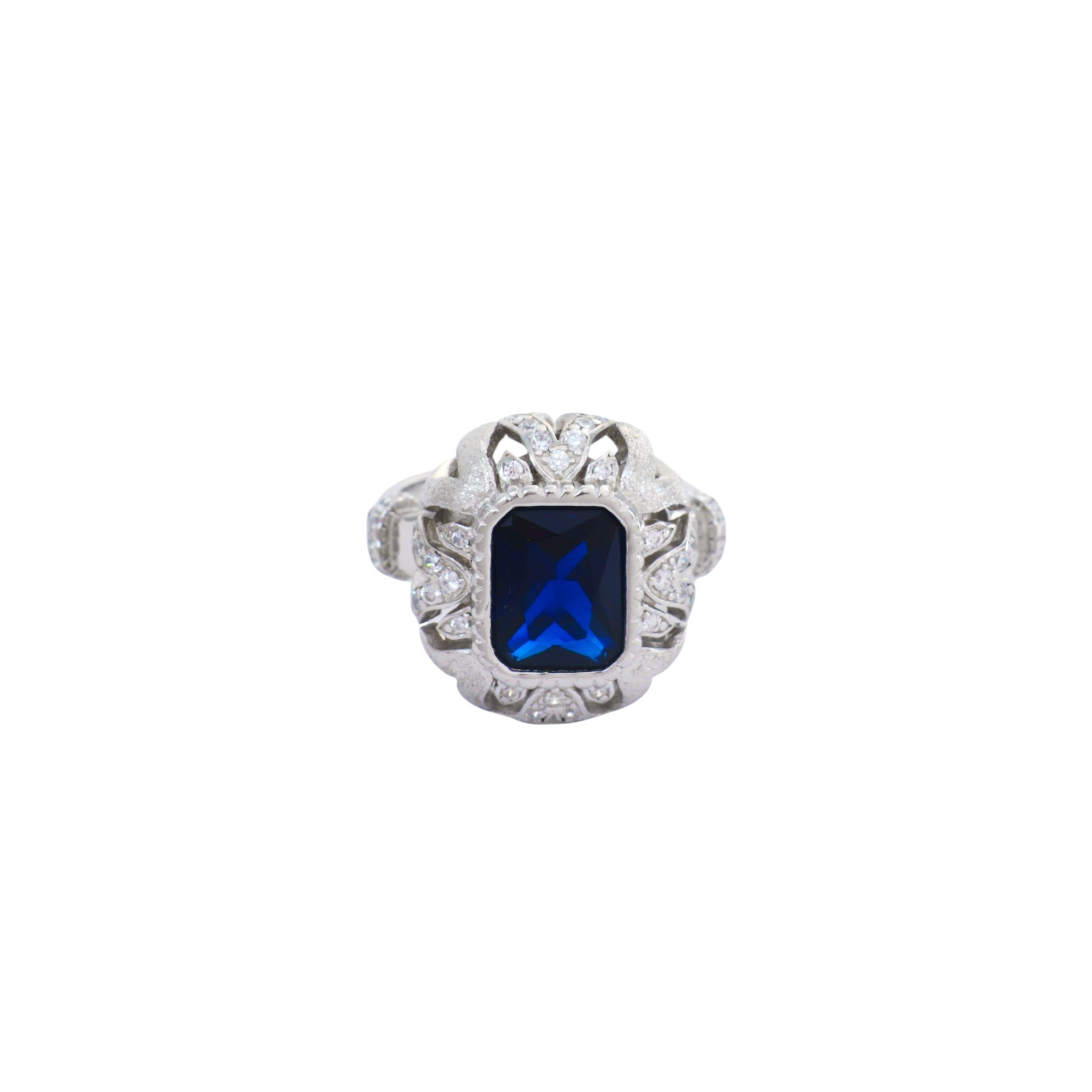 Deep sapphire blue emerald-cut gem encased in a detailed filigree scroll frame set in silver.