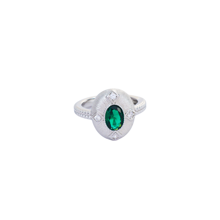 Oval emerald green stone set inside a brushed silver medallion with pave corner points.