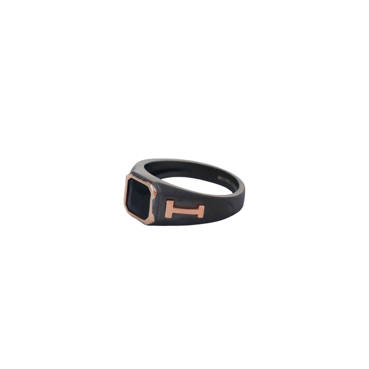 Dark matte black ring featuring a square black gem set with rose gold H-bar side motifs.