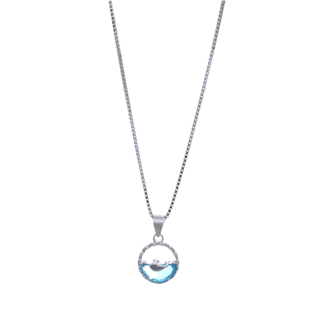 A silver chain necklace holding a circular pendant featuring a whale silhouetted against a light blue crystal wave.